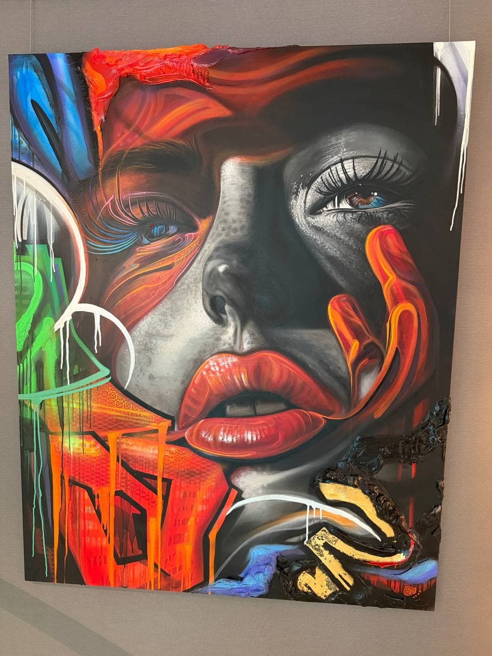 Chronodermism Neon Noir II by Rudy Hetzer, a large mixed media portrait with a grayscale face, red lips, blue eyes, orange fingers, neon red, green, blue, and white forms, drips, and black-and-gold textured layers.