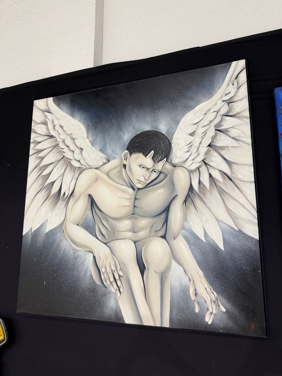 9Juane$ artwork Los showing a crouched winged male figure against a smoky dark background.