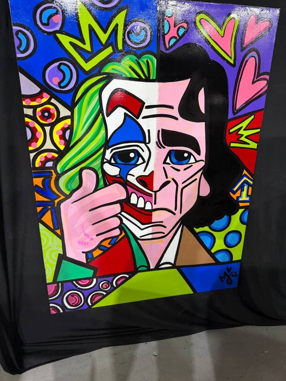 Mely G Art placeholder-titled pop portrait showing a split-face figure with mask-like geometry, green hair detail, hearts, crown shapes, and saturated graphic pattern.