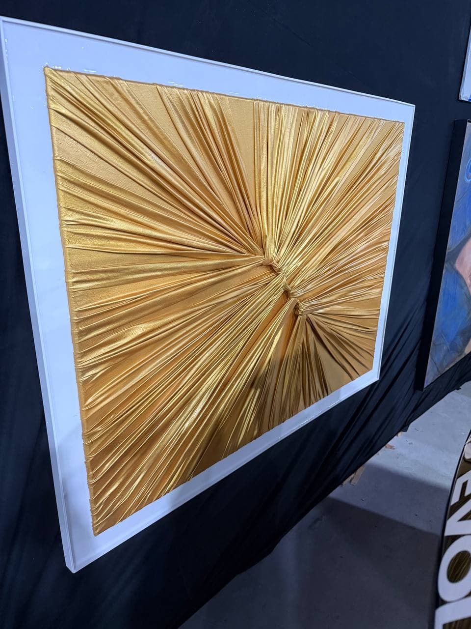 Tanya Goldmay Semenova artwork Gold Zone showing a radiant pleated gold sculptural surface converging into textured points inside a white frame.