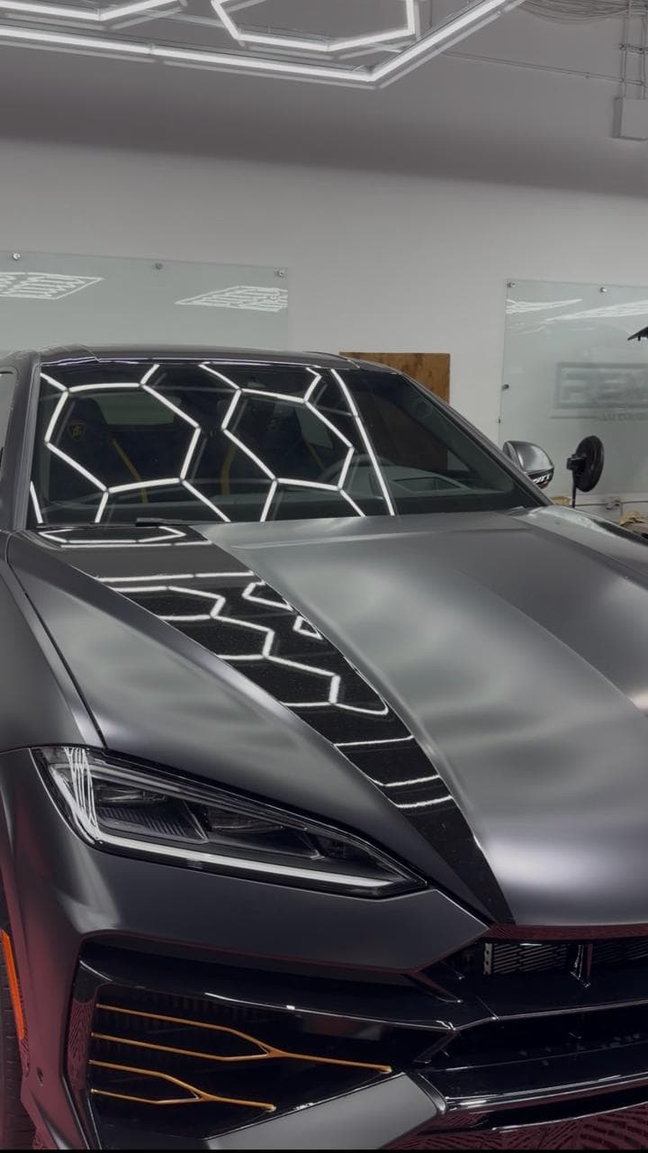 Matte exotic car hood and windshield under geometric showroom lights