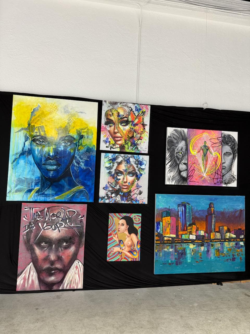 Contemporary art installed on the black gallery wall inside Revos Auto Group.